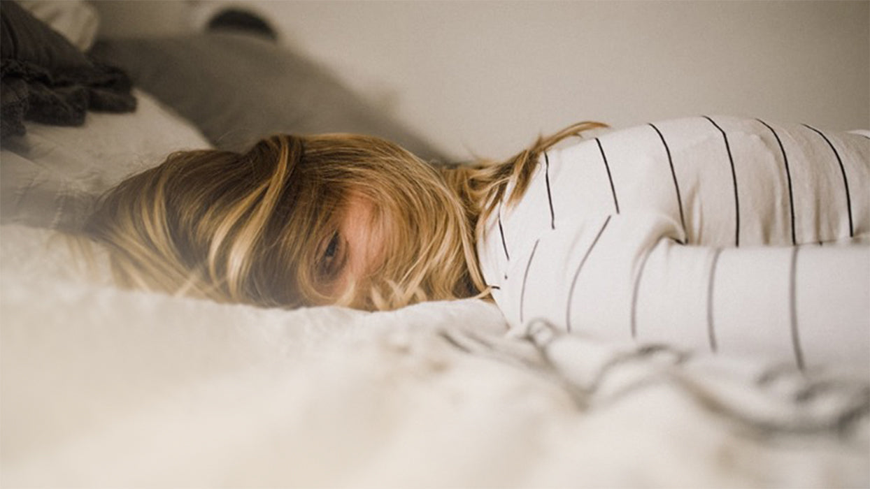 Muede Frau liegt auf dem Bett